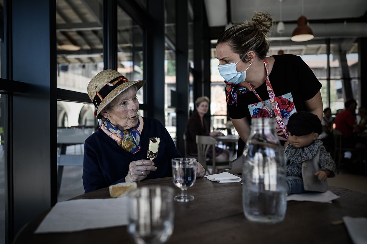 A volunteer (R) attending an Alzheimer’s patient during lunch at the restaurant of the village Landais Alzheimer site for Alzheimer’s patients in Dax, southwestern France. Credit: AFP