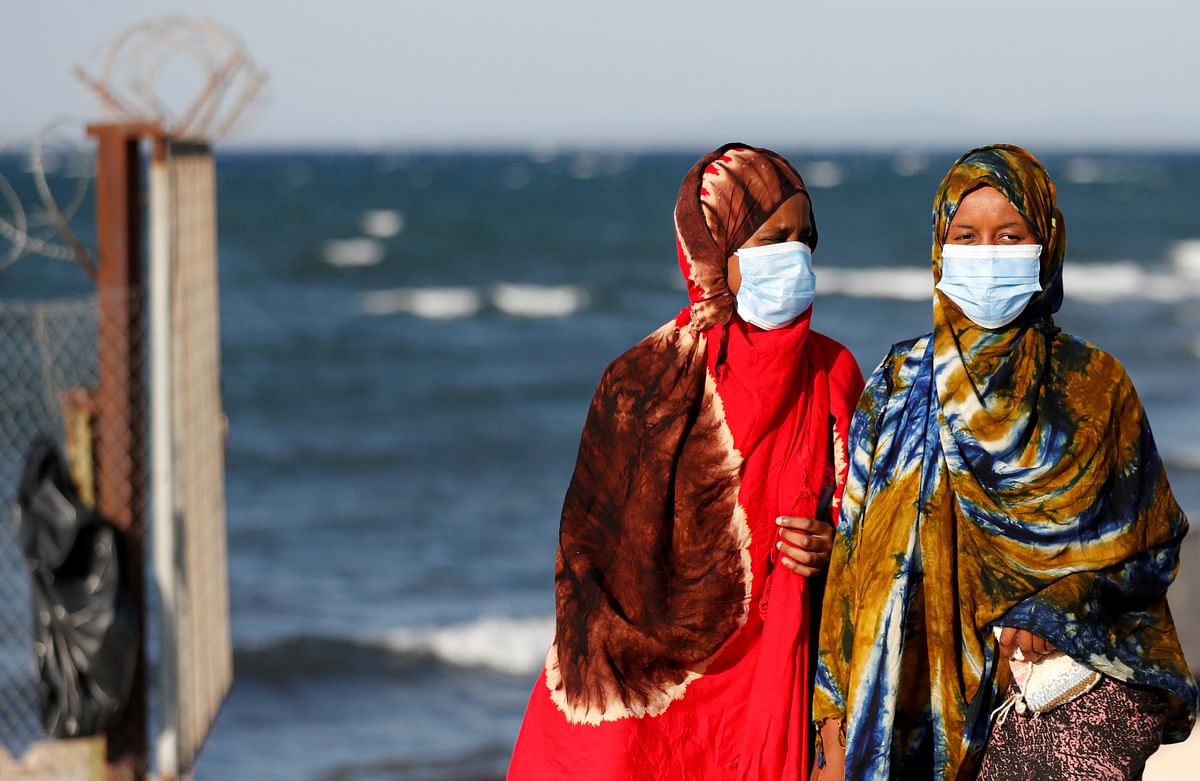 Women wearing face masks are seen at the entrance of a new temporary camp for migrants and refugees, on the island of Lesbos, Greece. Credit: Reuters