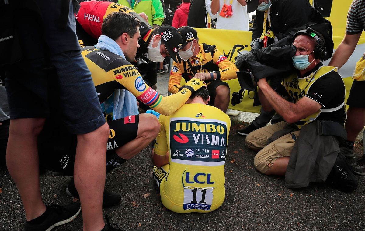 Team Jumbo-Visma rider Primoz Roglic of Slovenia, wearing the overall leader's yellow jersey, is comforted by teammates Tom Dumoulin of the Netherlands and Wout Van Aert of Belgium after finishing. Credit: Reuters
