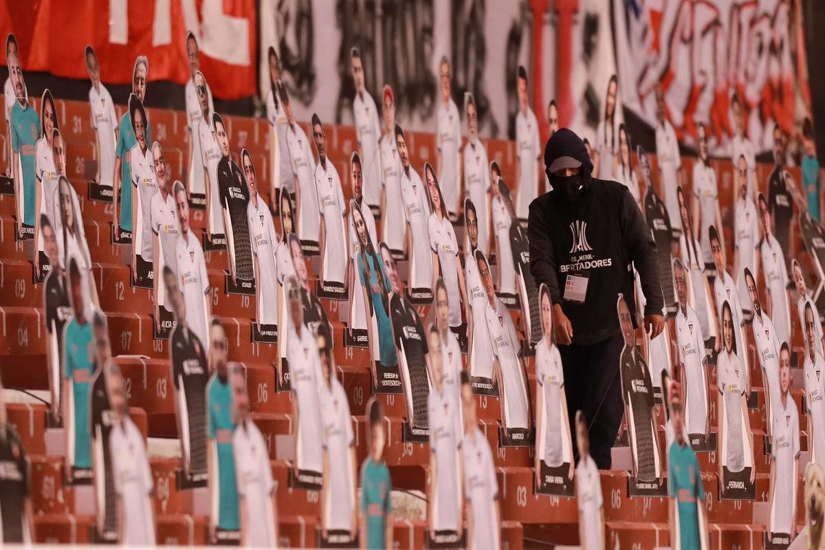 A man walks between cardboard figures of pictures of fans, on the stands before the start of the closed-door Copa Libertadores group phase football match between Ecuador's Liga de Quito and Brazil's Sao Paulo at the Rodrigo Paz Delgado stadium in Quito, amid the coronavirus pandemic. Credit: AFP Photo