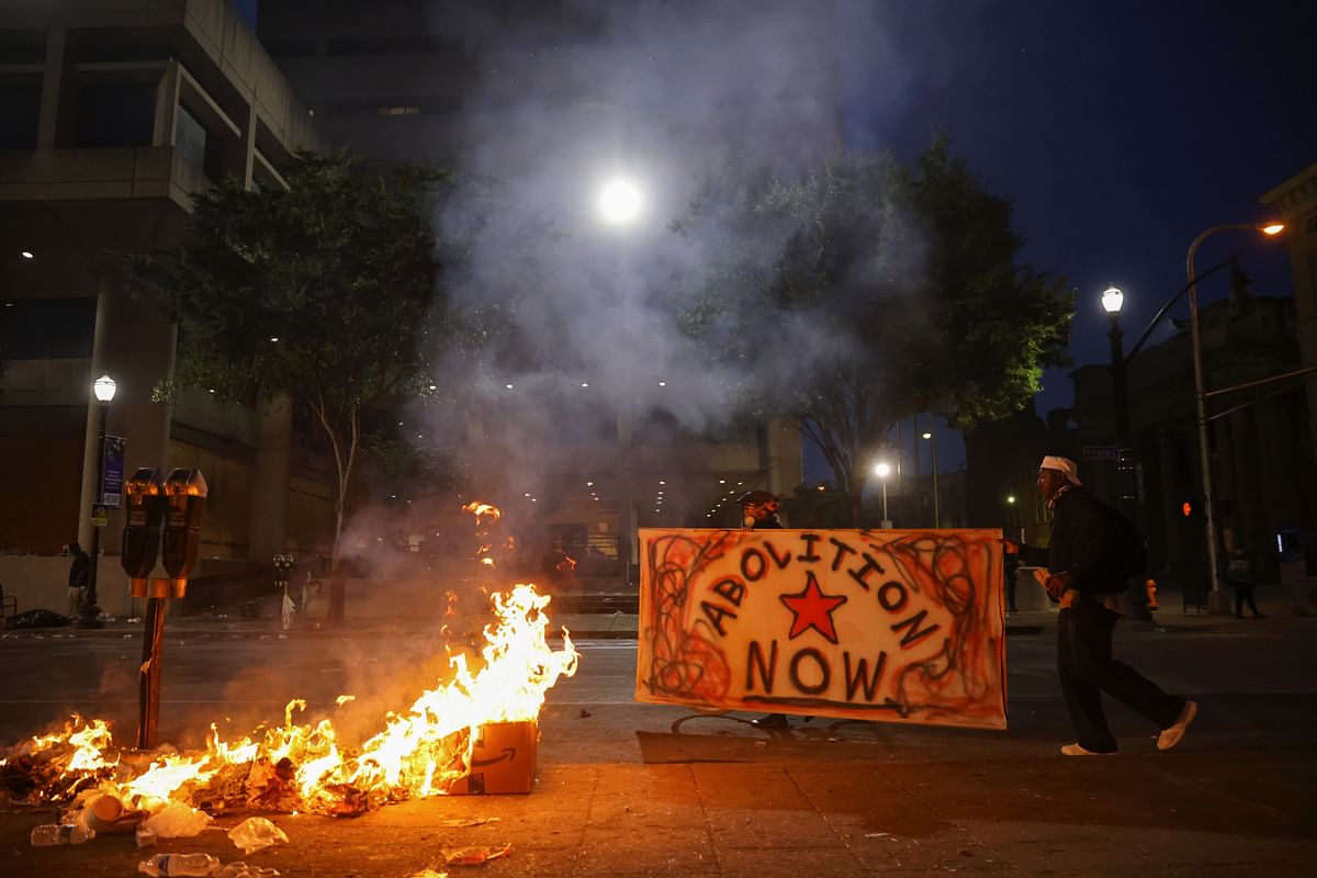 Protesters carry a sign as they walk by a fire in front of the Louis D. Brandeis Hall of Justice after a grand jury voted to indict one of three white police officers for wanton endangerment in the death of Breonna Taylor, who was shot dead by police in her apartment, in Louisville, Kentucky, US. Credit: Reuters