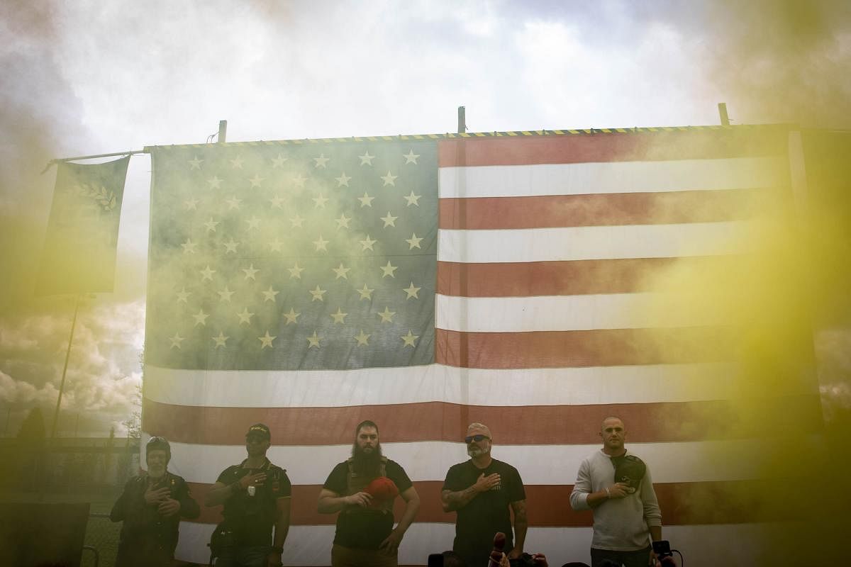 Yellow smoke fills the air as an American flag is raised at the start of a Proud Boys rally at Delta Park in Portland, Oregon on September 26, 2020. - Far-right group