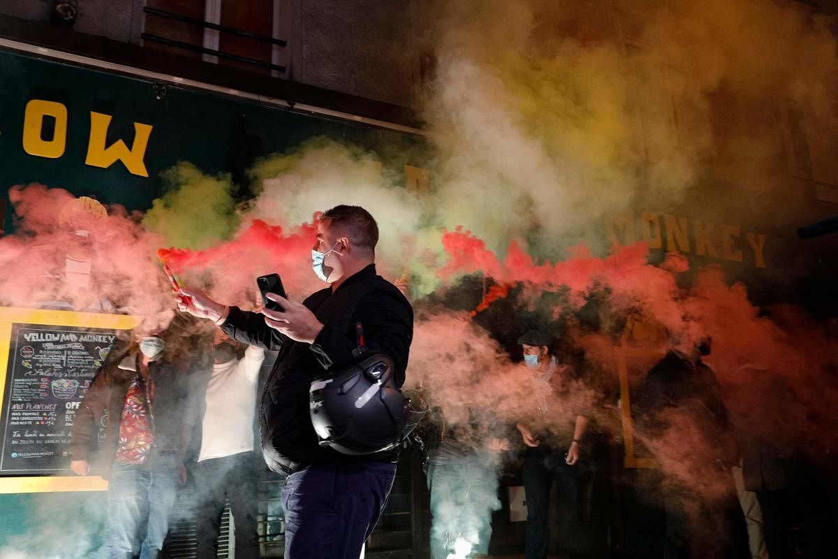 Restaurants and bars owners light flares as they protest in Paris, as the city is being forced to close bars and restaurants due to the health situation caused by the spread of the Covid-19 novel coronavirus. French government imposed fresh curbs to limit the spread of the virus, including on restaurants, bars and sports facilities. Credit: AFP Photo
