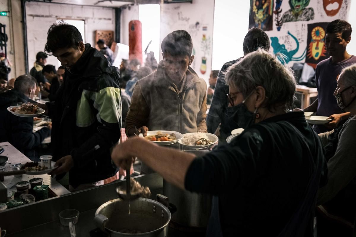 Afghan, Iranian and African migrants who arrived during the night have a meal at the