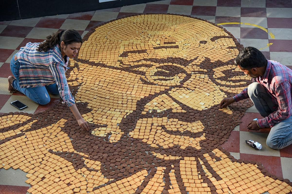 Artists Shailendra and Shatakshi create a mural of Mahatma Gandhi using around 5000 biscuits to mark his birth anniversary, at Boat club in Bhopal. Credit: PTI Photo