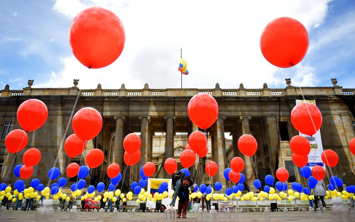 A woman places balloons with the colours of the Colombian national flag at Bolivar Square in Bogota, during a symbolic act commemorating the fourth anniversary of the referendum held to ratify a historic peace accord between the Colombian government and the FARC guerrilla, which voters narrowly rejected. Credit: AFP Photo