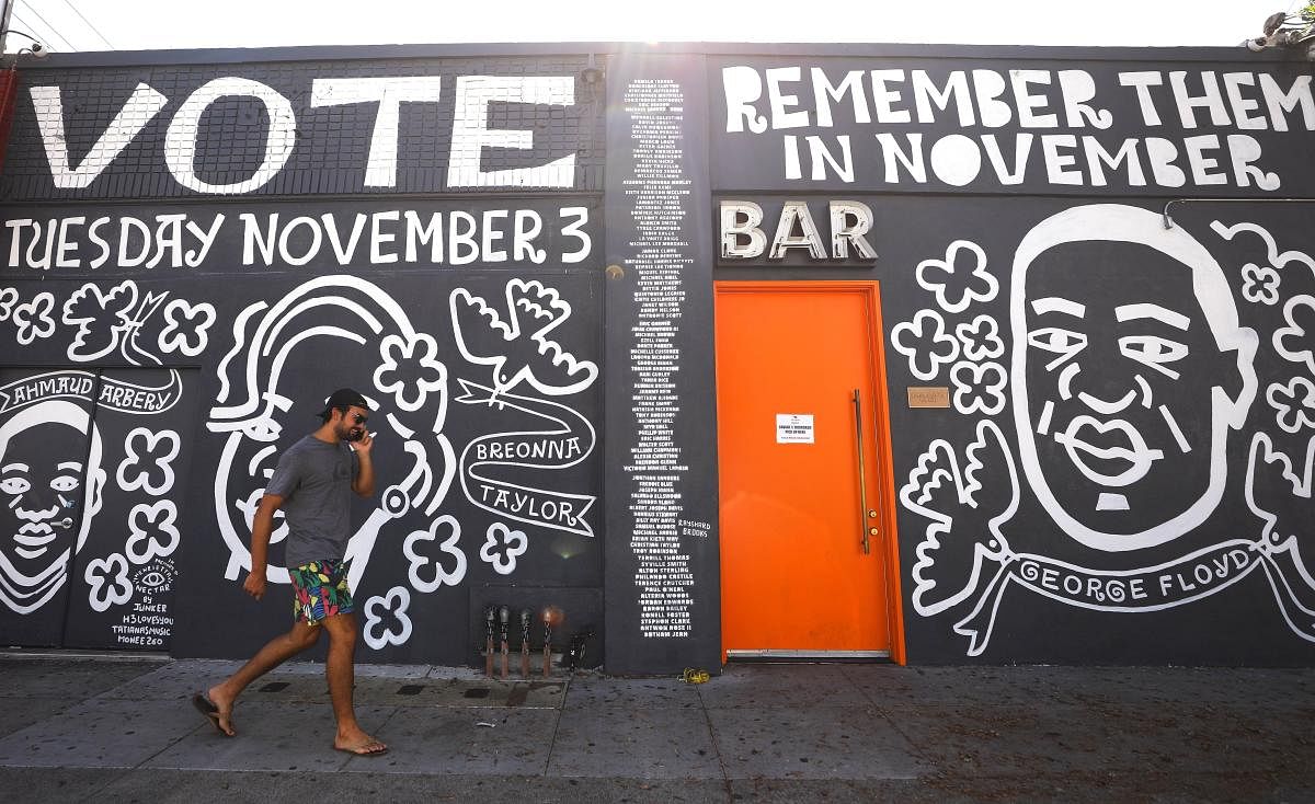 A man walks past a mural by artist Eric Junker which reads ‘Vote- Remember Them In November’ in Los Angeles, California. The mural features images of deceased Black shooting victims George Floyd, Breonna Taylor and Ahmaud Arbery. Floyd and Taylor were killed by police while Arbery was gunned down by two white men in Georgia while jogging. Credit: AFP Photo