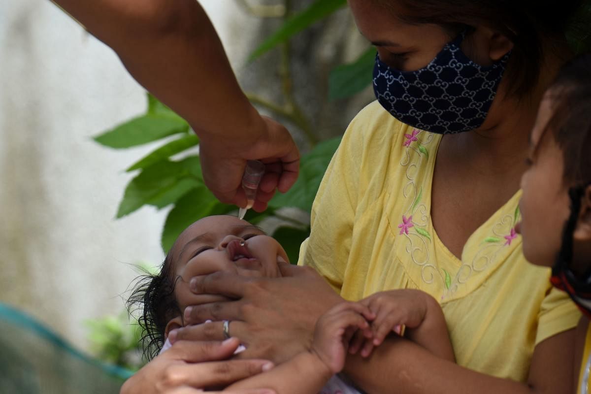A municipal health worker applying drops of a polio vaccine to a child at a relocation site for informal settlers in San Jose Del Monte in Bulacan province, north of Manila. Online misinformation is leaching out from cheap mobile phones and free Facebook plans used by millions of poor in the Philippines, convincing many to reject vaccinations for polio and other deadly diseases. Credit: AFP Photo