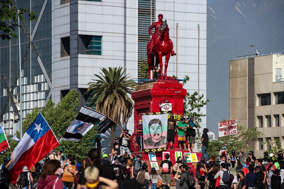 People protest by the General Baquedano monument -painted in red- against Chilean President Sebastian Pinera's government at Plaza Italia square, in Santiago. Credit: AFP Photo