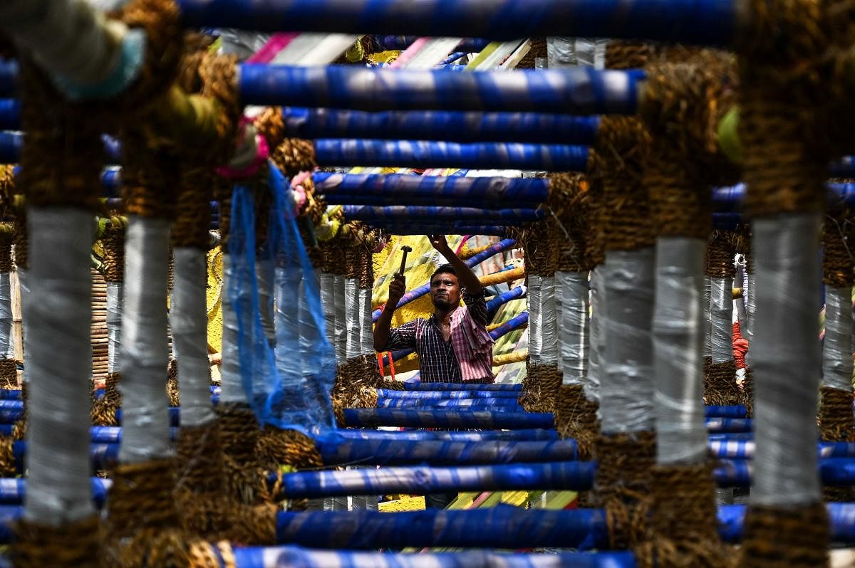 An artisan works on decorations near an idol of the ten-armed Hindu Goddess Durga at a makeshift place for worship, ahead of the Hindu festival 'Durga Puja' in Kolkata. Credit: AFP Photo
