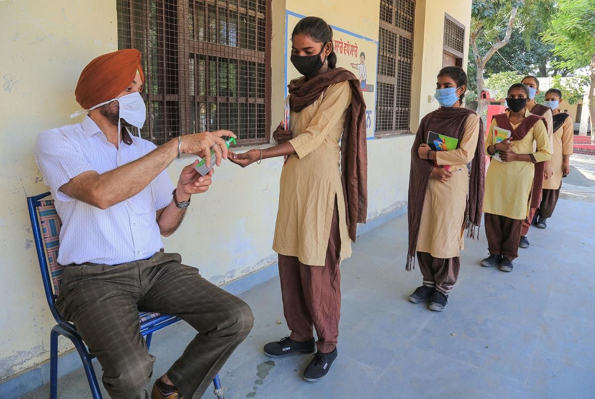 Students get their hands sanitised before entering a school after authorities allowed resumption of classes in Bathinda. Credit: PTI