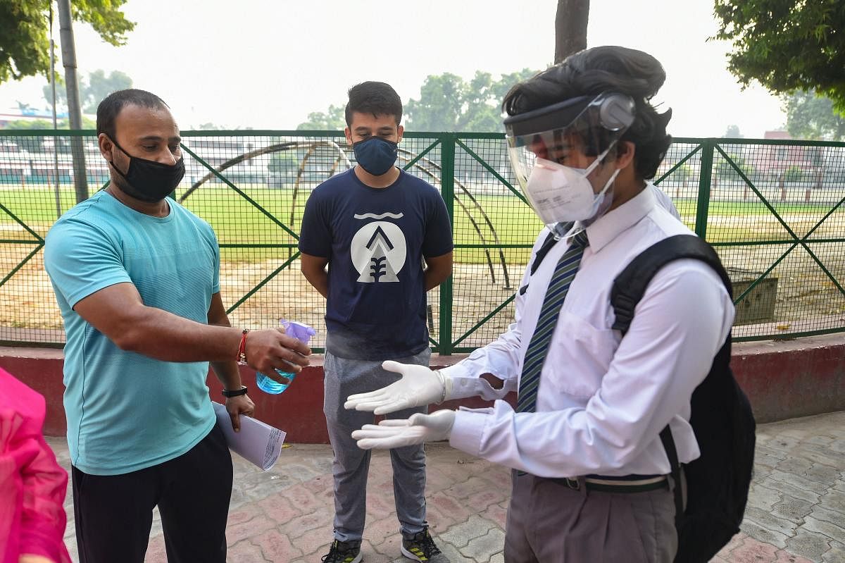 A student gets his hands sanitised before entering a school after authorities allowed resumption of classes for senior students of class 9 to 12 with certain restrictions in Lucknow. Credit: PTI