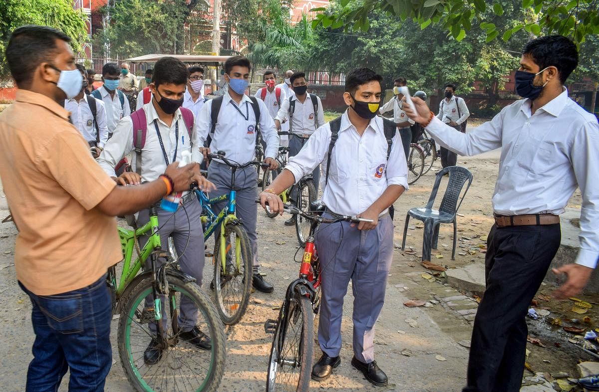 Students wearing face masks undergo thermal screening as they arrive at a school that was reopened as part of Unlock 5 after remaining closed for months due to coronavirus pandemic in Prayagraj. Credit: PTI