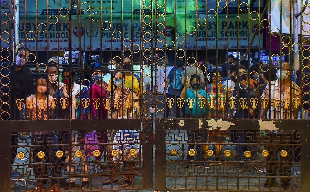 Visitors look at the pandal and Devi Durga through the closed gates, in Kolkata. Credit: PTI Photo