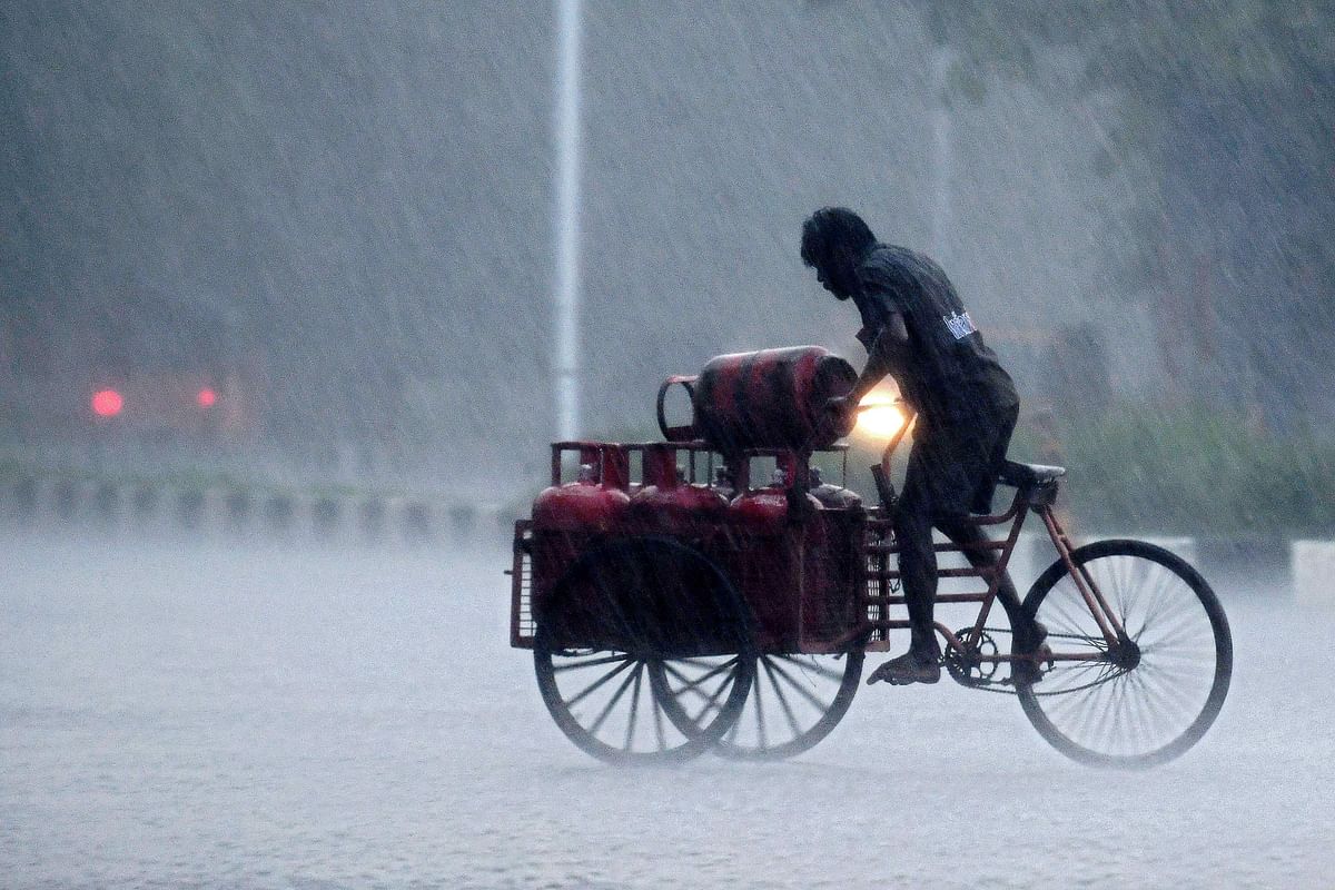 A Liquefied petroleum gas (LPG) distribution worker rides a cart loaded with gas canisters during a heavy rainfall in Chennai. Credit: AFP Photo