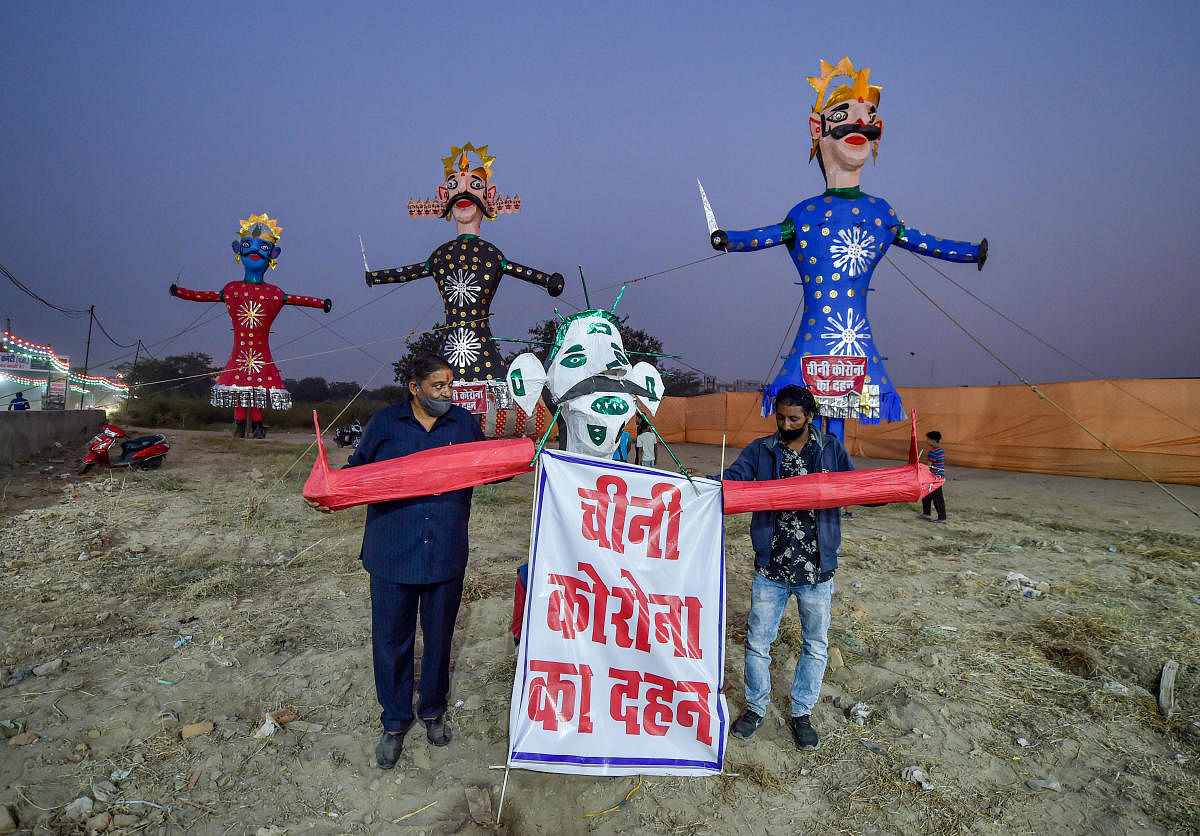 Committee members and craftsmen work on a 'corona effigy' of demon King Ravana at Balaji Ramlila Committee ground, ahead of Dussehra festival, in East Delhi. Credit: PTI Photo