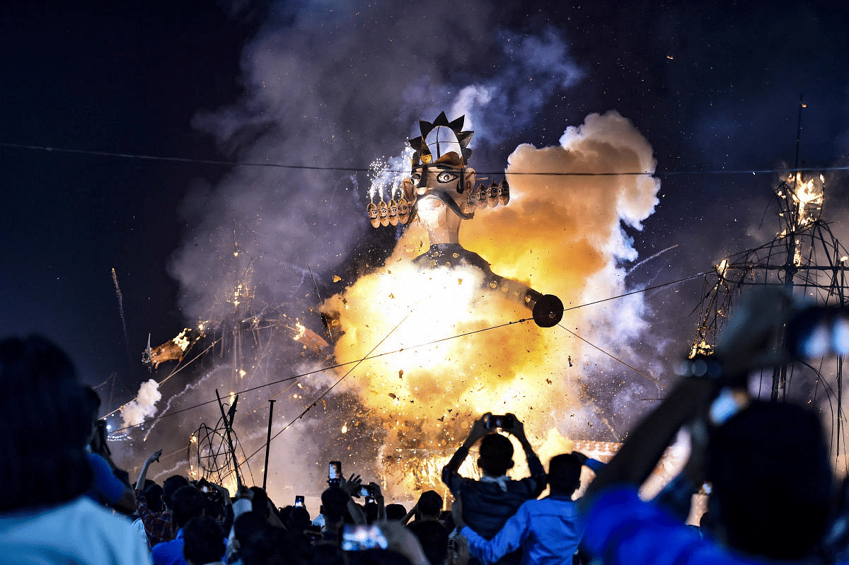 People look on as an effigy of demon king Ravana burns during Dussehra festival, at Karkardooma in New Delhi. Credit: PTI Photo