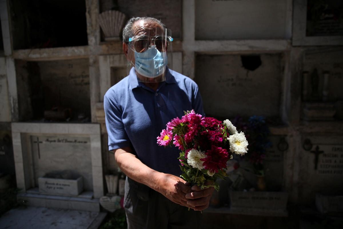 A man holds a bouquet of flowers while visiting the grave of his relative at a cemetery ahead of All Saints Day, amid the Covid-19 outbreak, in Santiago, Chile. Credit: Reuters.