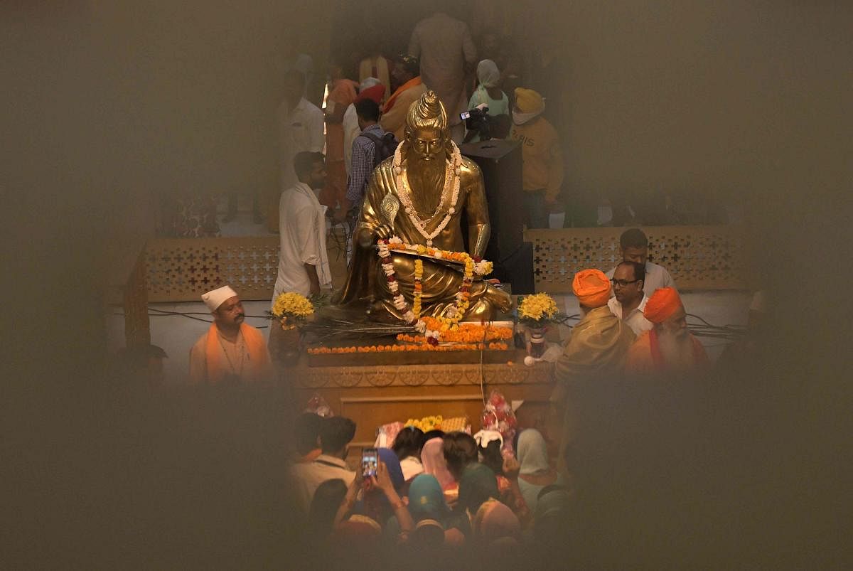 Hindu devotees pay respect to an idol of Bhagwan Valmiki at the illuminated Bhagwan Valmiki Temple in Ram Tirath, some 15 km from Amritsar, on the eve of the birth anniversary of Sanskrit poet Bhagwan Valimiki Jayanti. Credit: AFP Photo