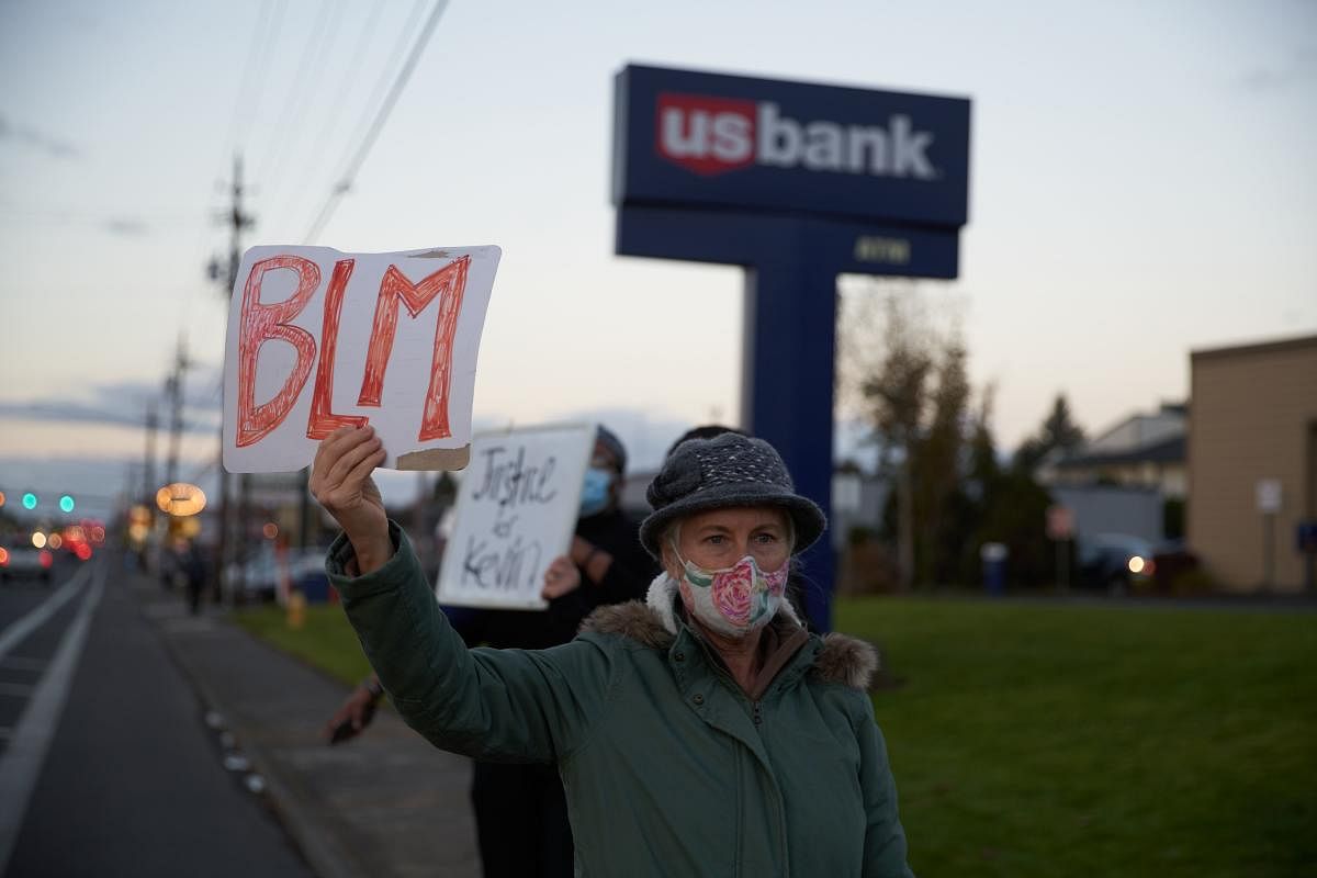 A woman holds a BLM (Black Lives Matter sign) in front of the location where Kevin Peterson Jr., a 21-year-old Black man, was fatally shot by police on October 29, 2020, on October 30, 2020 in Vancouver, Washington. Credit: AFP Photo