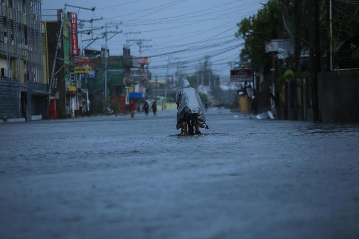 A resident cycles along a flooded street due to heavy rains brought by Super Typhoon Goni in Legazpi City, Philippines' Abay province. Credit: AFP Photo