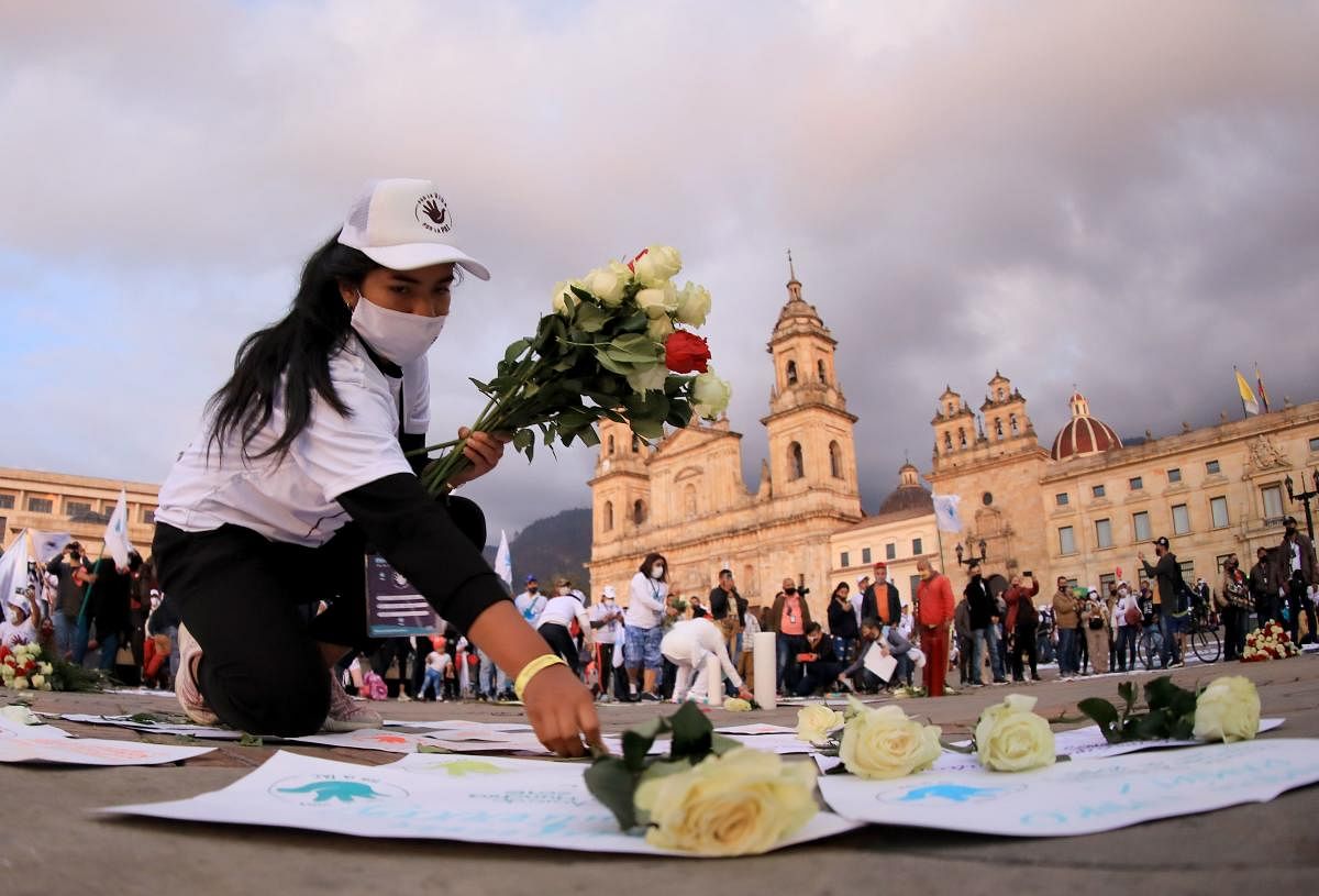 A woman places flowers in the ground during a demonstration demanding that peace accords should be respected, at the Bolivar square in Bogota. Credit: AFP Photo