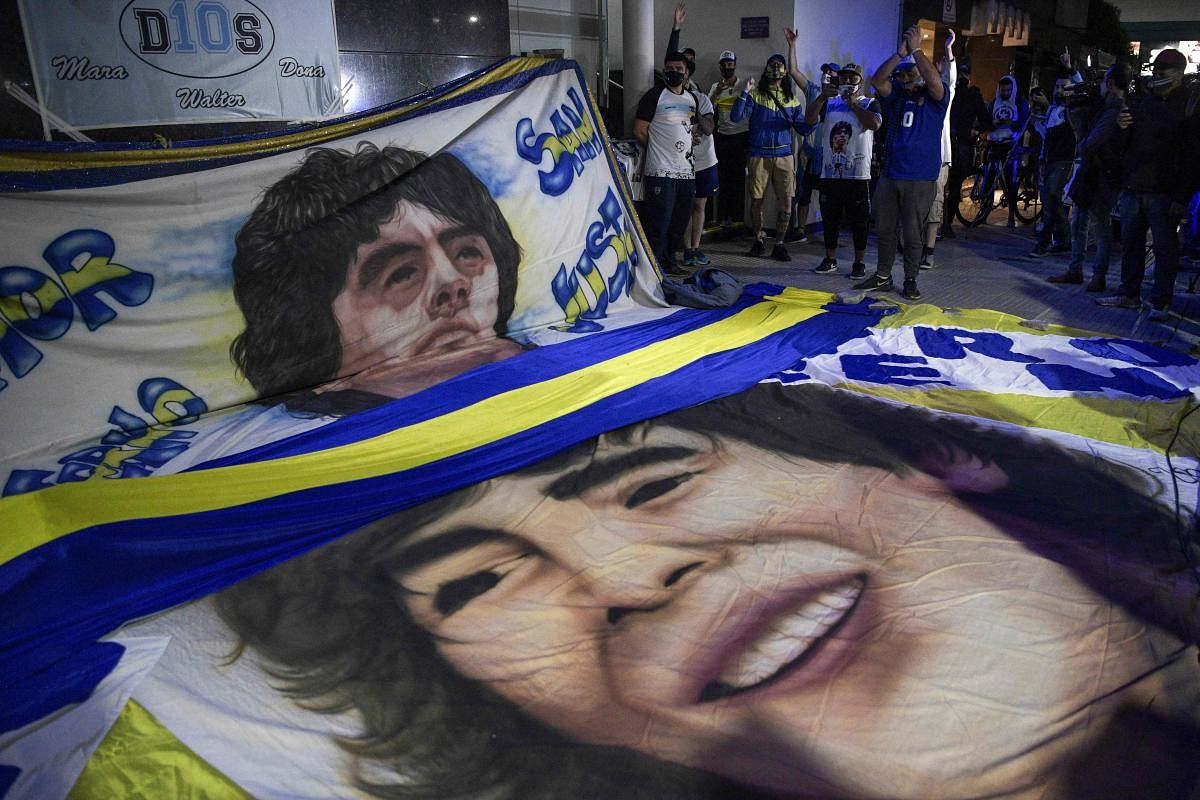 Supporters of Argentine former football star and coach of Gimnasia y Esgrima La Plata Diego Maradona gather outside the hospital where he undergoes a brain surgery for a blood clot, in Olivos, Buenos Aires. Credit: AFP Photo