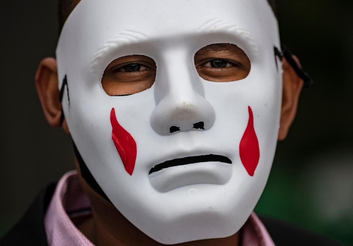 A relative of a victim of the Palace of Justice's siege by the members of the M19 guerrilla, wears a mask during a demo in Bogota on its 35th anniversary. Credit: AFP Photo