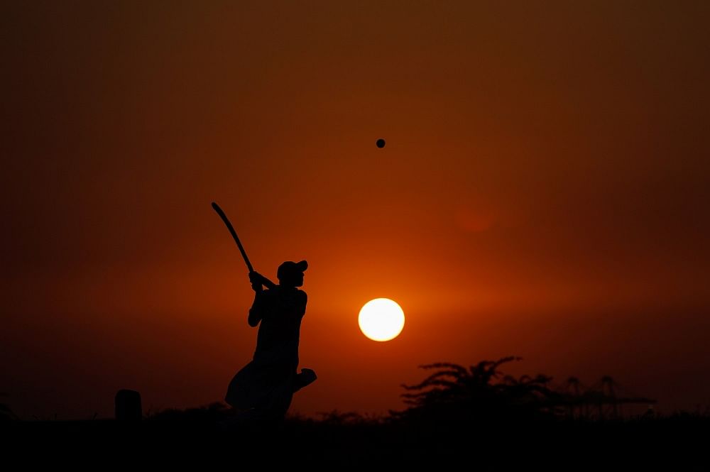 A man is silhouetted against the setting sun as he plays cricket amid the coronavirus disease (COVID-19) outbreak, in Karachi, Pakistan. Credits: Reuters Photo