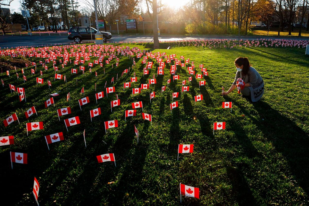 A healthcare worker places miniature Canadian Flags outside the Sunnybrook Hospital on November 10, 2020 ahead of Remembrance Day in Toronto, Ontario, Canada. Credits: AFP Photo