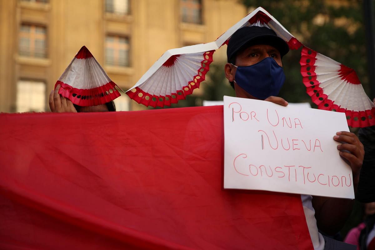 A member of Peruvian community living in Chile holds a sign reading 'for a new constitution' during a rally to support their compatriots in Santiago, Chile. Credit: Reuters Photo