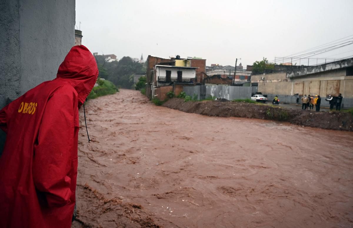 Locals look at the rising level of the Chiquito river, in La Hoya neighbourhood, in Tegucigalpa, following the passage of Hurricane Iota. Hurricane Iota barrelled through Central America, after making landfall earlier this week as the strongest Atlantic storm this year along a stretch of Nicaraguan coast devastated by a powerful storm just two weeks ago. Credit: AFP Photo