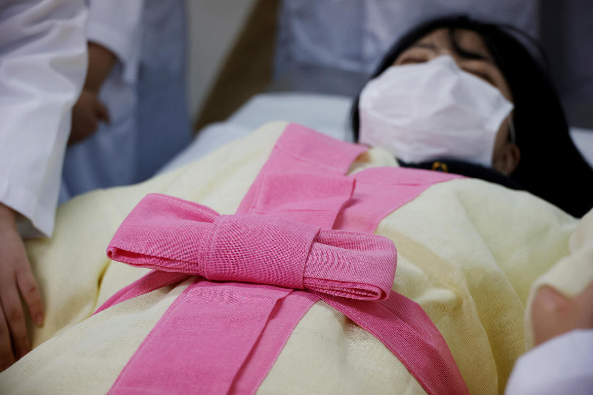 Park Se-jung who majors the funeral directing at Eulji University, is laid for practice of how to shroud the deceased during a class, in Seongnam, South Korea. Credit: Reuters Photo