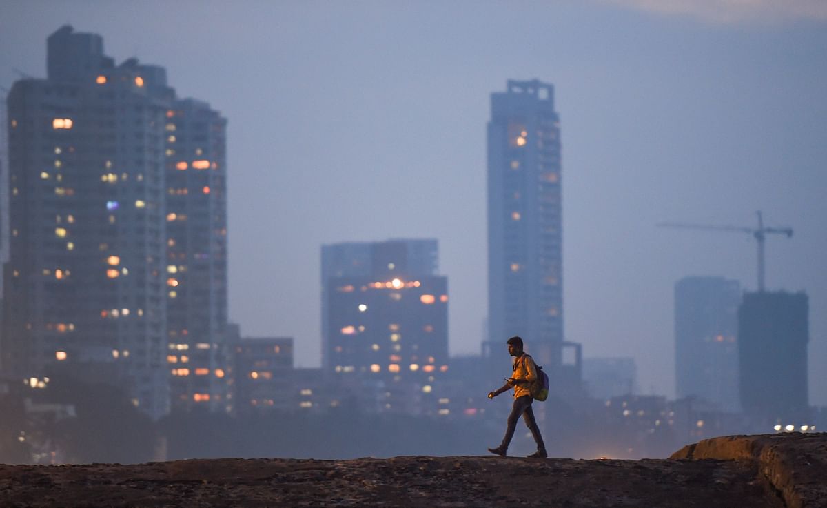 A man walks along Dadar beach as smog engulfs the city skyline, in Mumbai. Credit: PTI Photo