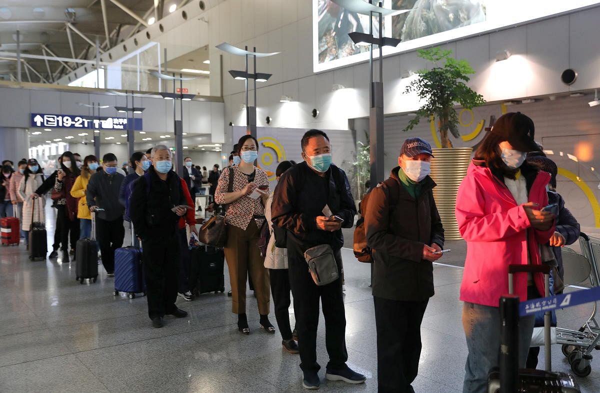 Travellers wearing face masks line up to board a flight at Beijing Capital International Airport, following the global outbreak of the coronavirus disease, in Beijing, China. Credit: Reuters Photo