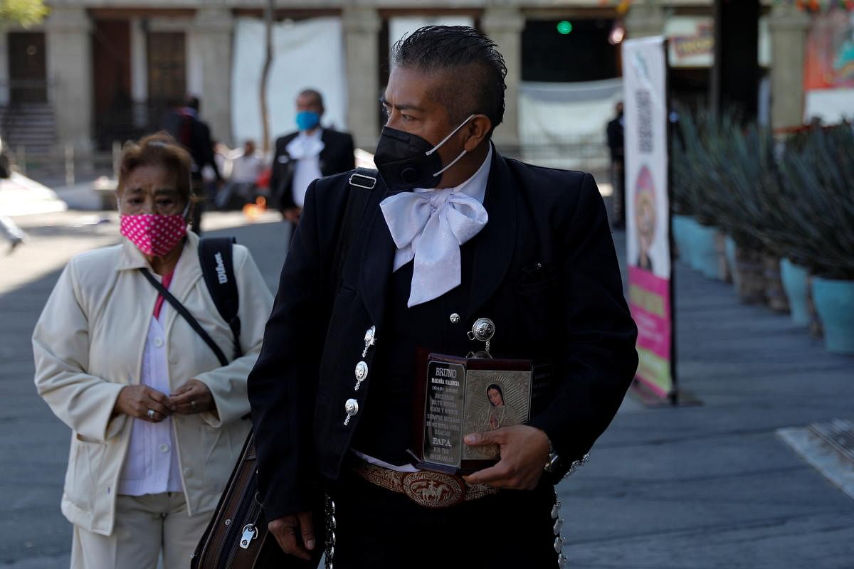 Mariachi Sergio Magana carries the ashes of his late mariachi father, who died of Covid-19, as he pays homage to Saint Cecilia, the patron saint of musicians, during the annual celebration as the Covid-19 outbreak continues, in Mexico City, Mexico. Credit: AFP Photo