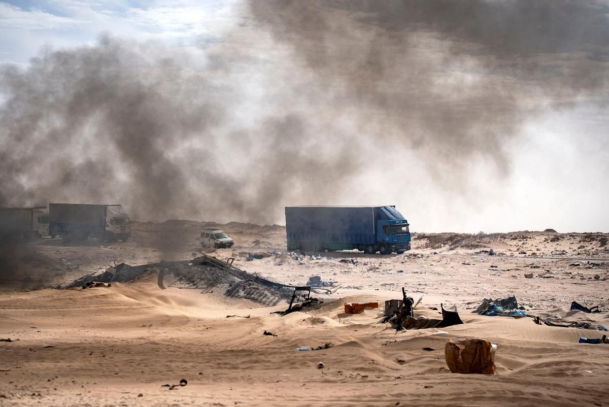 Trucks are pictured behind burning waste on a road between Morocco and Mauritania in Guerguerat located in Western Sahara after the intervention of the royal Moroccan armed forces in the area. Morocco in early November accused the Polisario Front of blocking the key highway for trade with the rest of Africa and launched a military operation to reopen it. Credit: AFP Photo