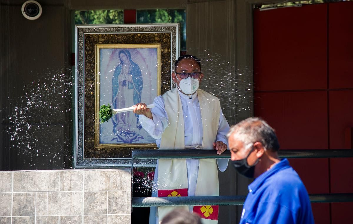 A priest wearing a face mask is seen blessing the faithful outside the Basilica of Guadalupe, in Mexico City. The Basilica of Guadalupe will remain closed from December 10 to 13 during the festivities of the Virgen Morena to avoid crowds and minimize the risks of possible contagion of Covid-19 among pilgrims, the government of Mexico City and the Catholic Church informed this Monday. Credit: AFP Photo