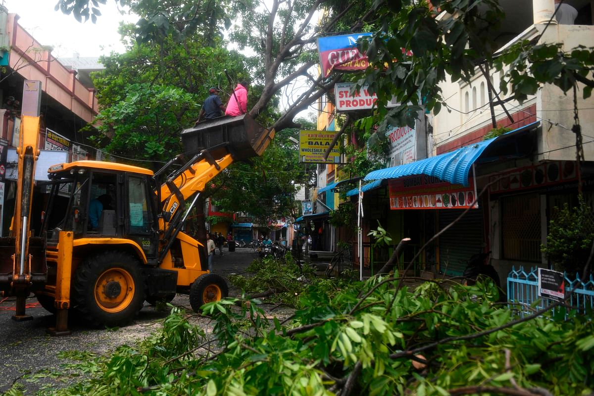 Emergency and rescue workers clear a street after a tree fell due to heavy rains and strong winds after after Cyclone Nivar landfall, in Puducherry on November 26, 2020. Credit: AFP Photo