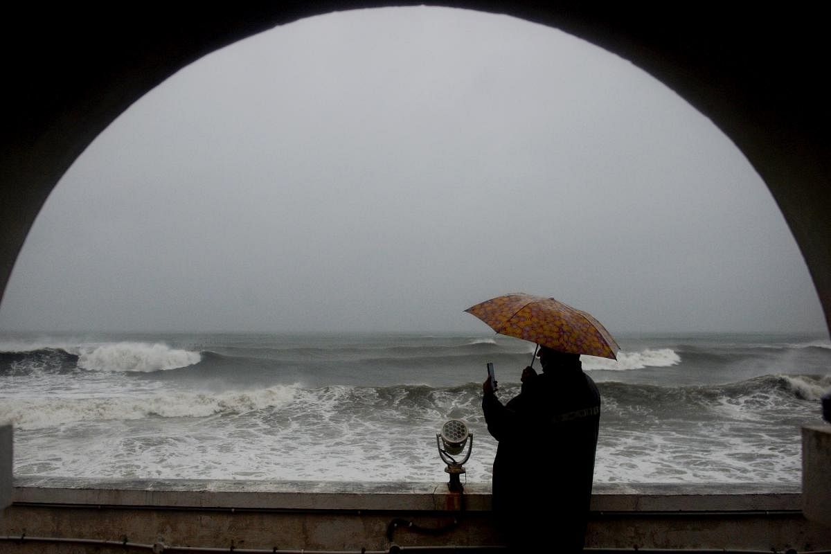 A man shelters under an umbrella from heavy rains while looking out to the Indian ocean as cyclone Nivar approaches the southeastern Indian coast in Puducherry. Credit: AFP Photo