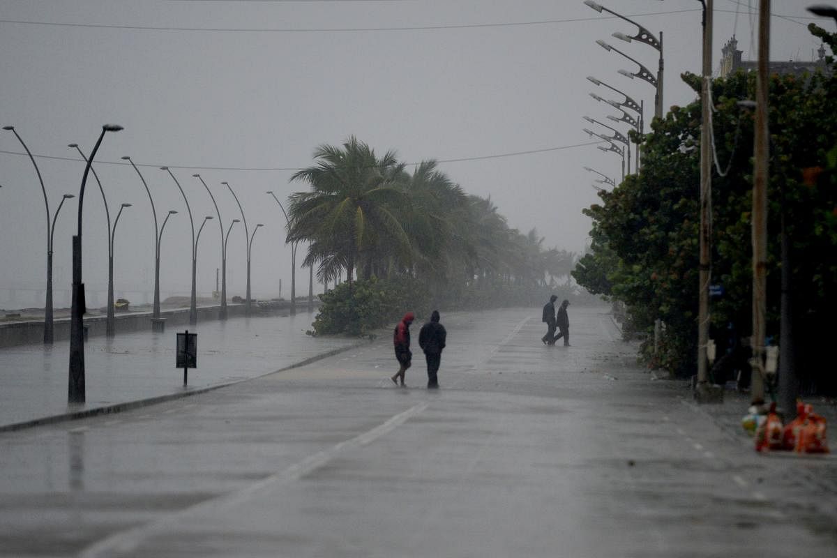Policemen walk along a deserted beach road during heavy rains as cyclone Nivar approaches the southeastern Indian coast in Puducherry on November 25, 2020. Credit: AFP Photo