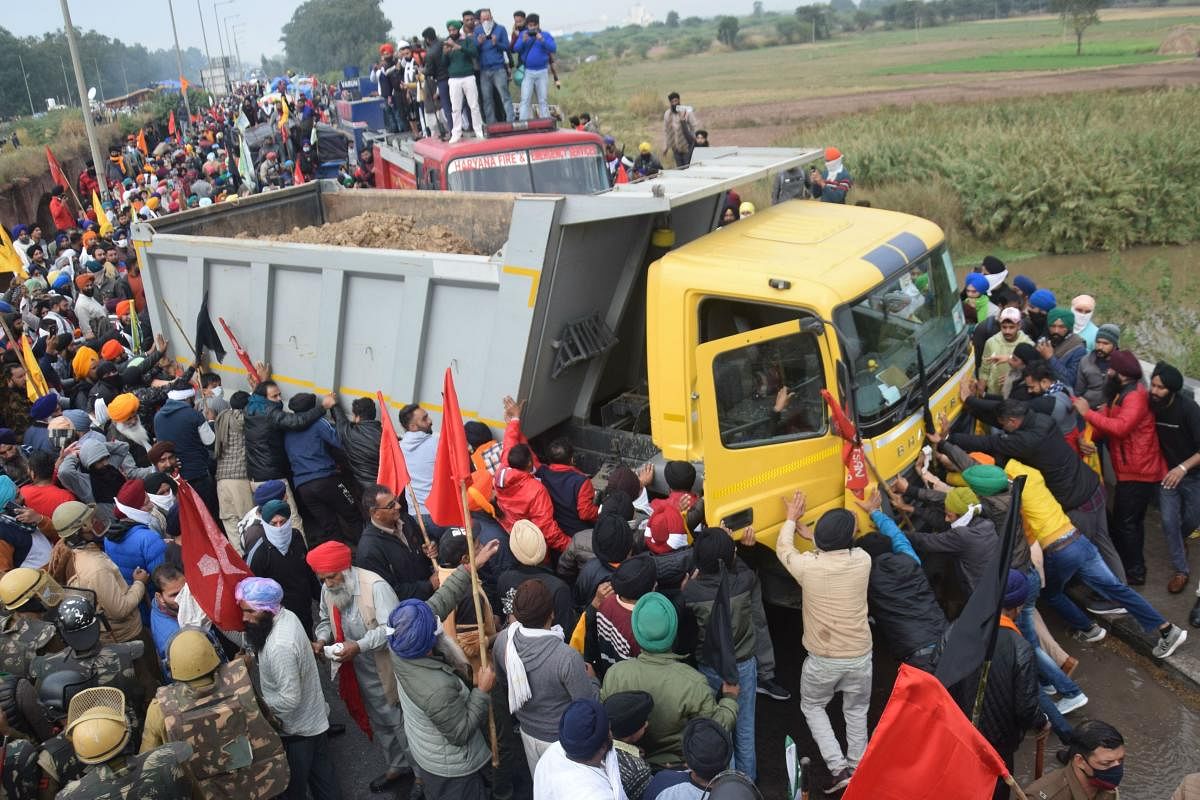 Farmers push a truck blocking a road during a march to India's capital New Delhi to protest against the central government's recent agricultural reforms, in Ambala on November 26, 2020. Credit: AFP Photo