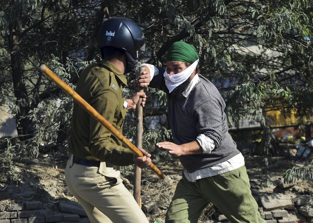 A security person and a farmer clash as protestors attempt to cross Singhu Border during 'Delhi Chalo' march against the new farm laws, in New Delhi. Credit: PTI Photo
