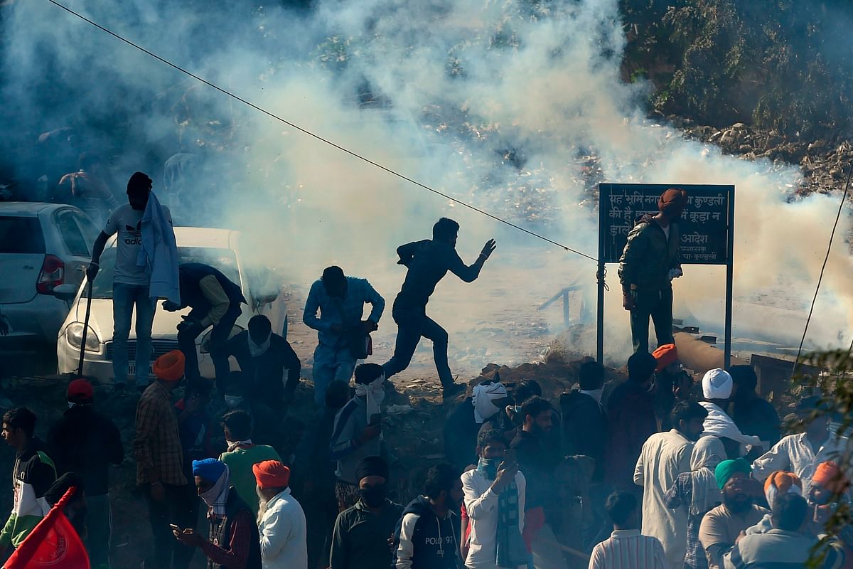 Police fire tear gas to disperse farmers at a roadblock as they try to march to New Delhi