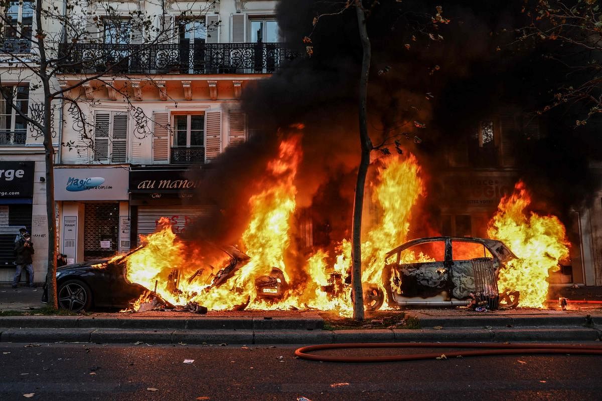 Parked vehicles are burning during a protest against the 'global security' draft law, which would criminalise the publication of images of on-duty police officers with the intent of harming their 'physical or psychological integrity', in Paris. Dozens of rallies are planned on November 28 against a new French law that would restrict sharing images of police, only days after the country was shaken by footage showing officers beating and racially abusing a black man. Credit: AFP Photo