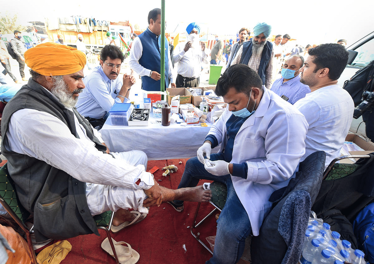 A medic provides first aid to a farmer during the 'Delhi Chalo' protest against Centre's new farm laws, at Singhu border in New Delhi. Credit: PTI Photo