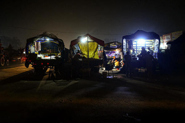 Farmers take rest on tractor-trolleys at night during their ongoing protest against the Centre's new farm laws, at Singhu border in New Delhi. Credit: PTI