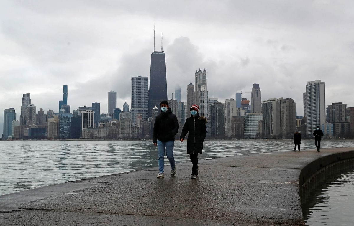 People wearing protective face masks walk, as the global outbreak of the coronavirus disease (COVID-19) continues, along the shores of Lake Michigan in Chicago, Illinois. Credit: Reuters
