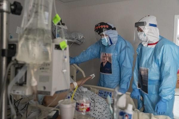 Dr. Joseph Varon, left, and other medical staff member talk to a patient in the Covid-19 intensive care unit (ICU) at the United Memorial Medical Center in Houston, Texas. Credit: AFP