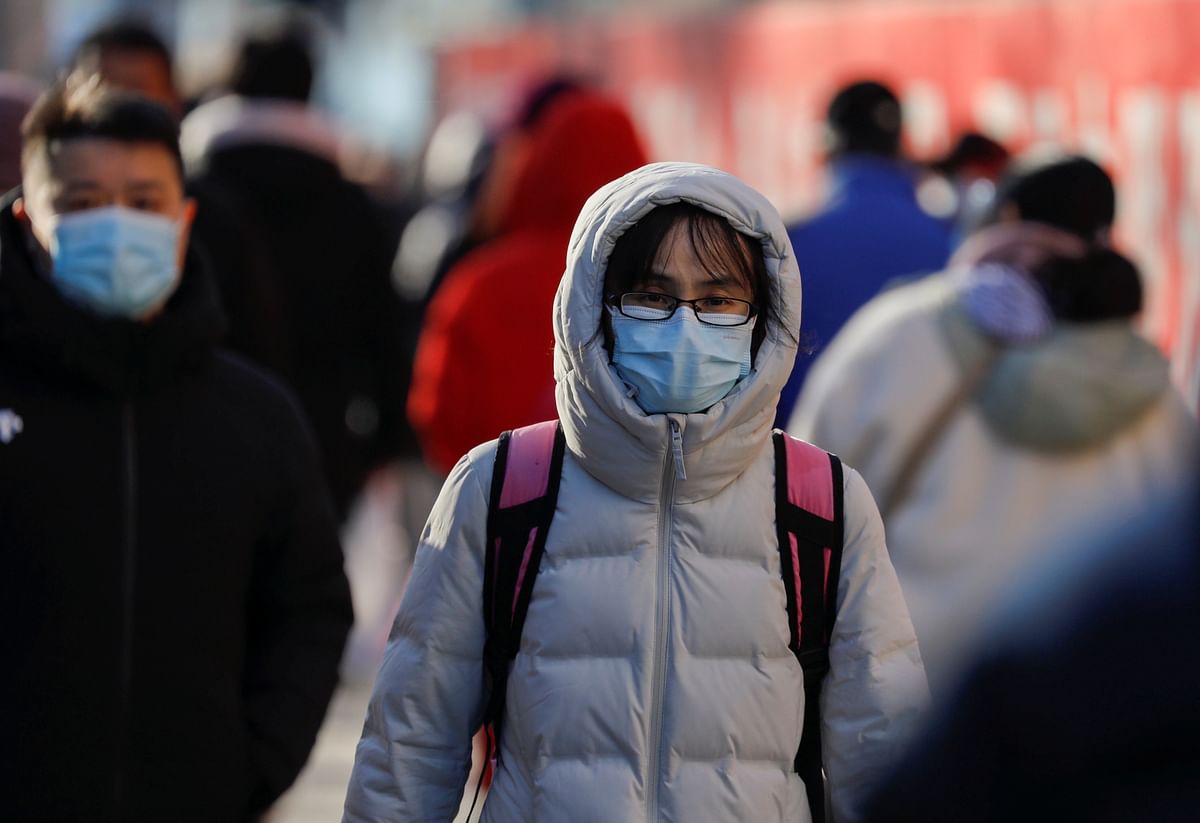 People wearing masks walk in a street in Beijing's central business district (CBD) during morning rush hour. Credit: Reuters